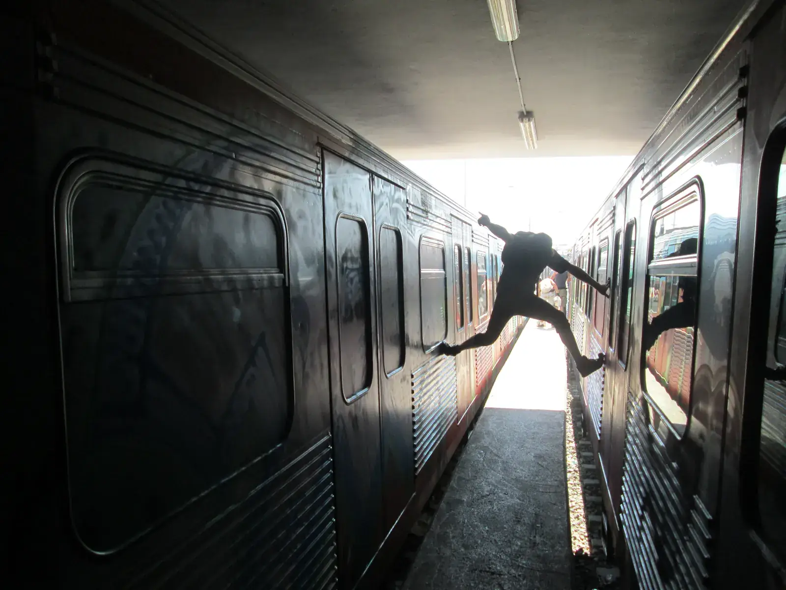 A man leaping between two subway cars