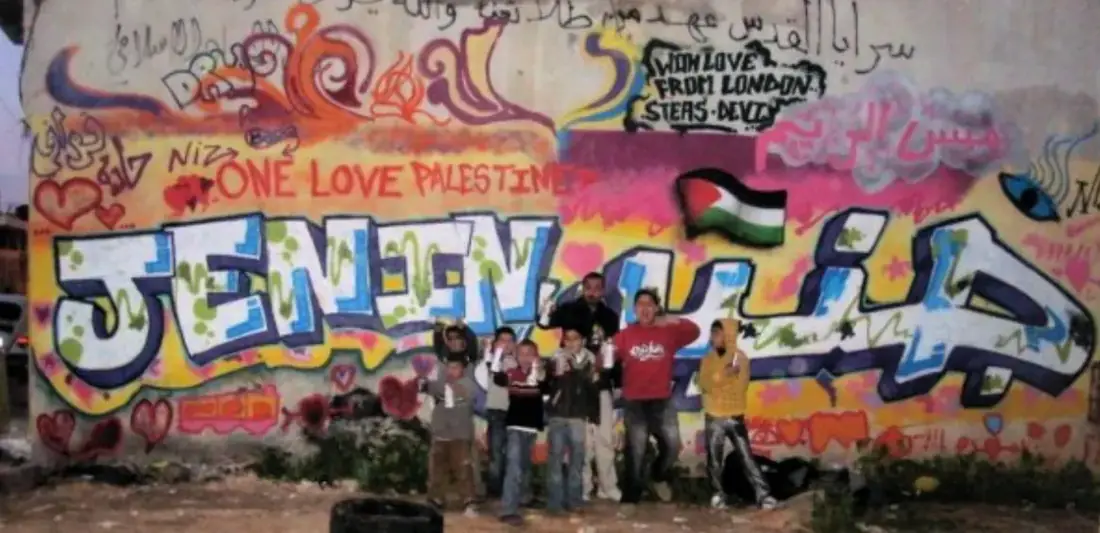 Children in front of a painted Jenin wall