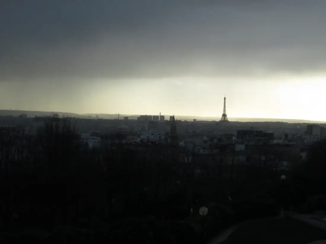Paris under a storm sky, with the Eiffel Tower in the distance