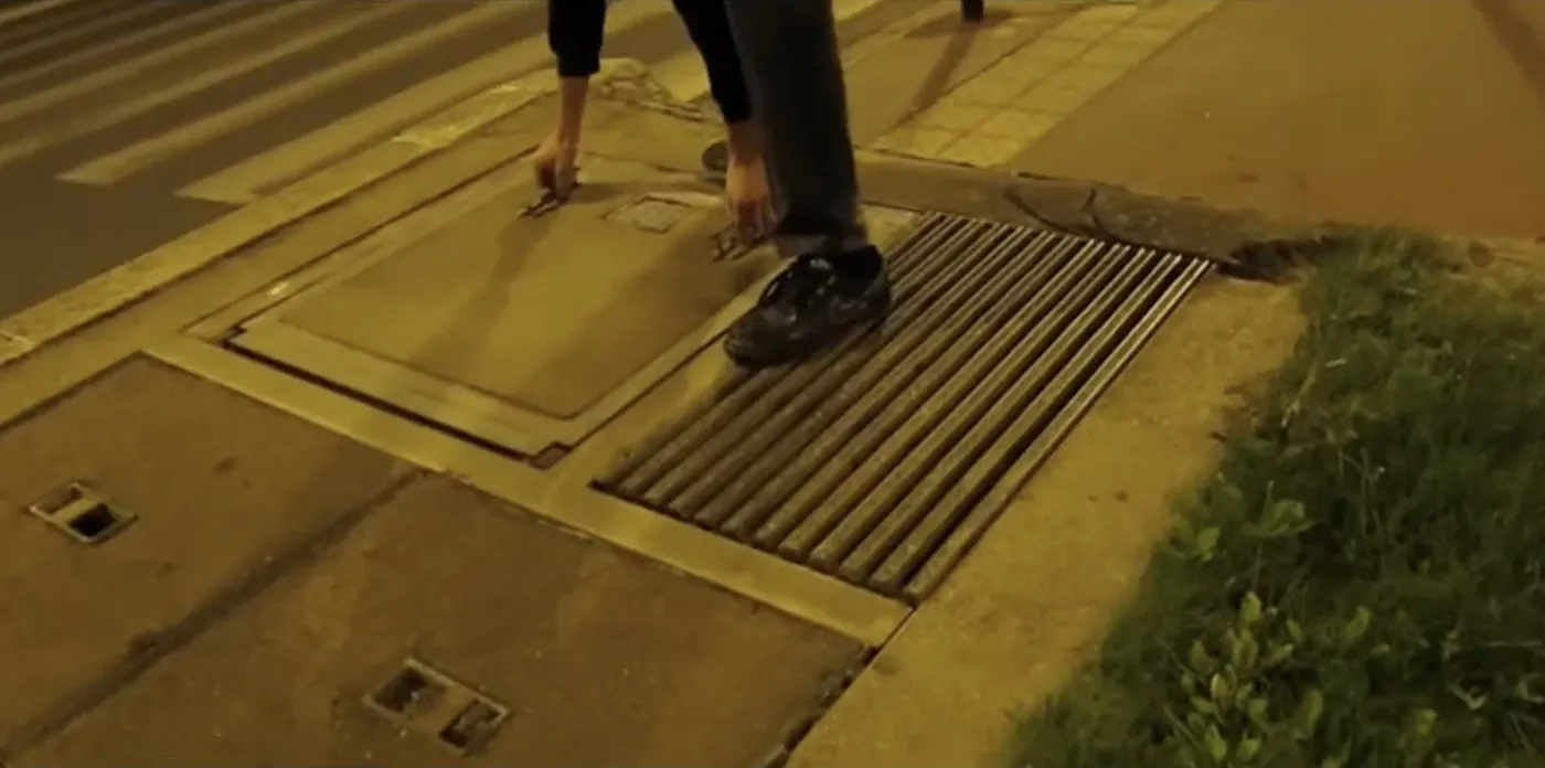 Lifting a street hatch on a Paris sidewalk at night